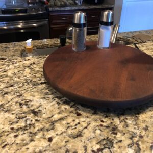 A wooden plate with two salt and pepper shakers on top of it.