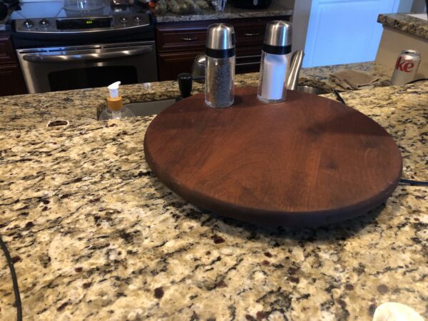 A wooden plate with two salt and pepper shakers on top of it.