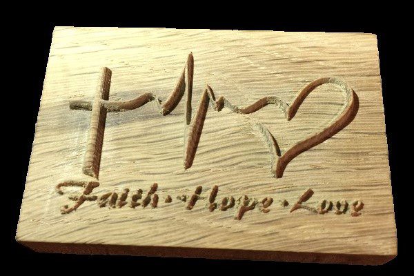 A wooden plaque with the word faith, hope and love engraved on it.