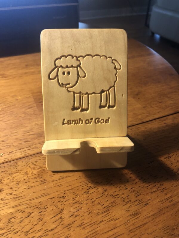 A wooden phone holder with an image of a sheep.